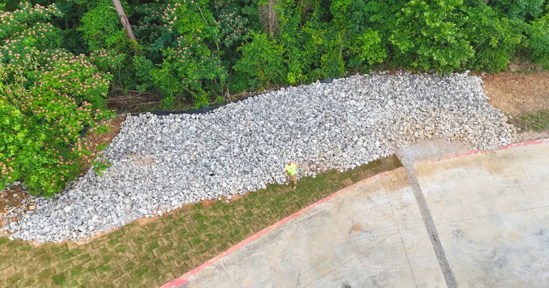 Rip rap stone drainage channel installed along a landscaped Alabama yard